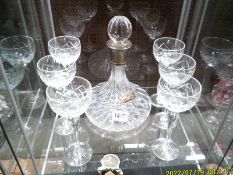 A cut glass ship's decanter with silver collar and lable together with six cut glass wine glasses.