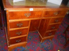 A light mahogany knee hole writing desk with centre cupboard and green leather top. COLLECT