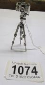 A silver camera on tripod, 25 grams.