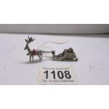 A small silver reindeer with sleigh.