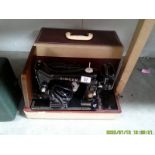 A cased vintage Singer electric sewing machine.