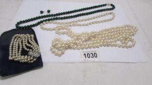 A green stone necklace with matching earrings, two pearl necklaces and a pearl bracelet.