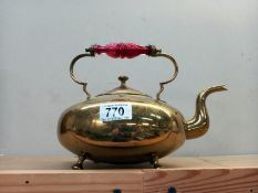 An old brass kettle with cranberry glass handle