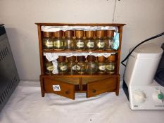 A hanging wooden spice rack with jars