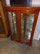 A bow front, mirror backed, display cabinet
