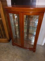 A bow front, mirror backed, display cabinet