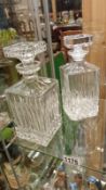 2 crystal decanters with square stoppers.