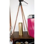 A vintage camera tripod on spike legs and a brass spent shell