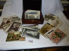 A mixed lot of old postcards and photographs in a mahogany box.