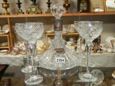 A silver top decanter with silver label and 6 glasses.