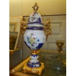 A porcelain lidded urn on metal base.