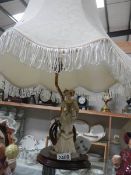 A figural table lamp with large shade.