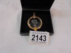 An engraved glass pendant in yellow metal mount.