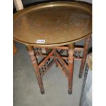 An early 20th century folding table with brass top.