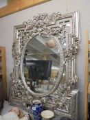 A large contemporary bevel edged mirror in ornate silver coloured frame. COLLECT ONLY