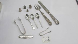 Three silver tea spoons, silver sugar nips, silver thimbles, silver handled knife and fork etc.,