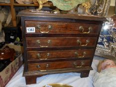 A small mahogany four drawer chest with brass handles.