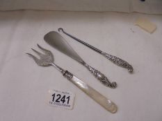 A silver fork with mother of pearl handle together with a silver handled shoe horn and button hook.