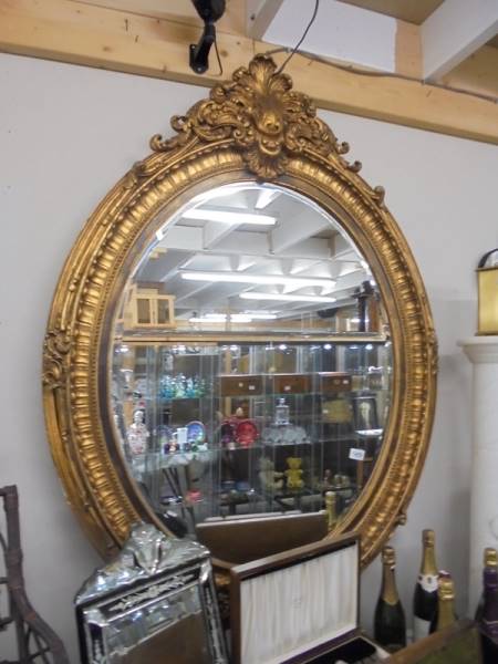 A large oval bevel edged mirror in gilded frame COLLECT ONLY.