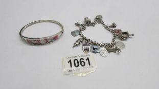 A silver bangle and an old silver charm bracelet with twelve charms.