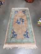 A beige/green Chinese dragon rug (61" x 30")
