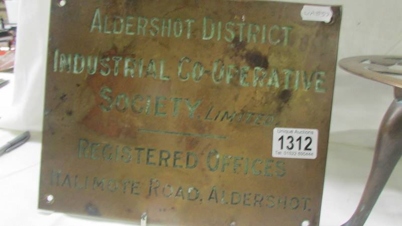 A Brass Aldershot co-op sign and a large oval brass trivet. - Image 2 of 3