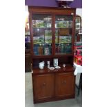 A dark wood stained wall unit with cut glass doors (45cm x 92 cm x 196 cm high). Collect Only.