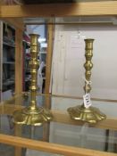 A pair of brass candlesticks on petal shaped bases and with pushers.