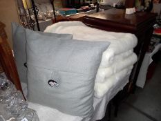 A pair of grey cushions and 3 white faux throws.