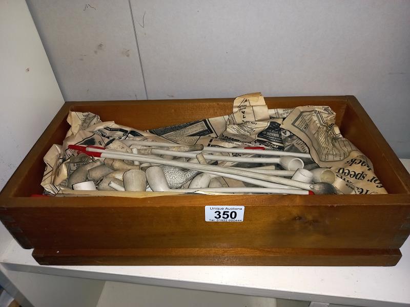 A wooden box containing old clay pipes.