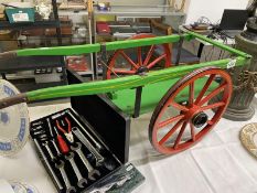 A vintage painted wooden scale model of a hand cart.