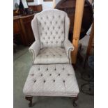 A deep buttoned wing armchair with footstool.