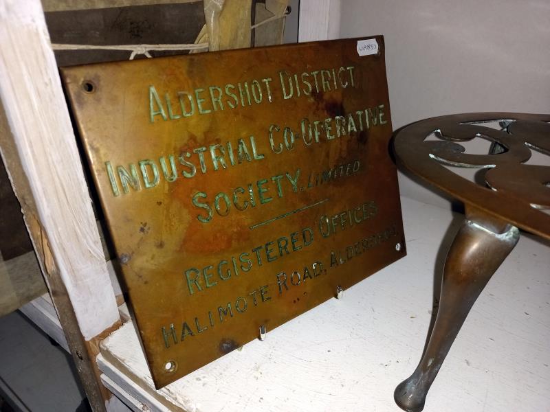 A Brass Aldershot co-op sign and a large oval brass trivet. - Image 2 of 3