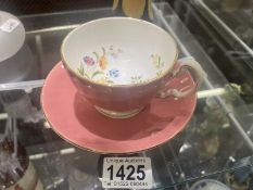 An Aynsley pink cup and saucer, butterfly garden design in cup. (Small chip near the rim of the