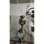 A brass oil lamp with chimney and four spare chimneys