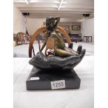 A bronze nude figure sitting on a hand on a marble base.