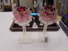 A pair of glass candleholders with cranberry glass shades.