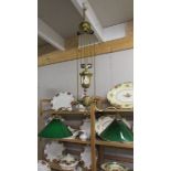 A brass art nouveau twin arm rise and fall ceiling light with green and white glass shades.