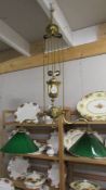 A brass art nouveau twin arm rise and fall ceiling light with green and white glass shades.