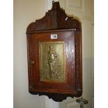 A small oak hanging corner cupboard with art nouveau style metal panel in door.