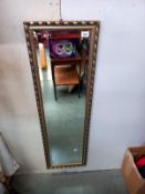 A gilt framed bevelled edge mirror. 37cm x 124cm.