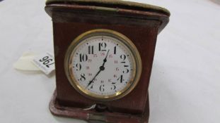 A vintage travel clock in leather case, in working order.