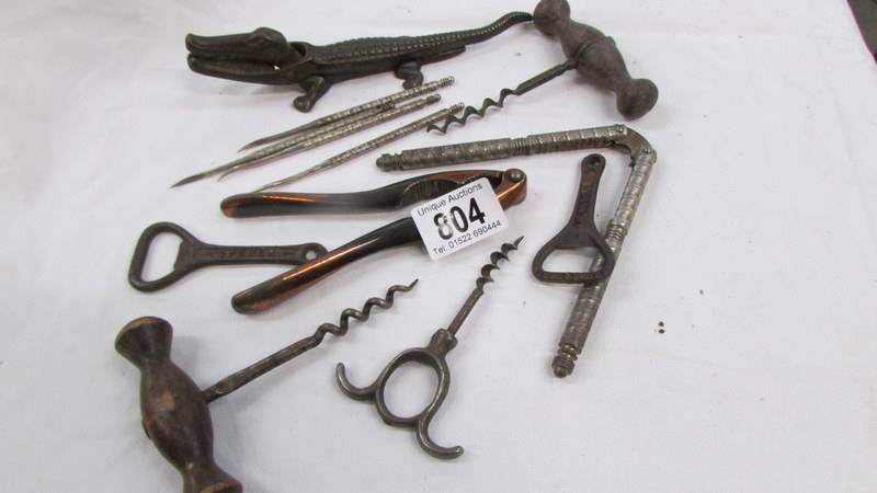 A vintage cast iron crocodile nut cracker, cork screws and bottle openers.