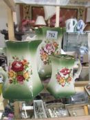 A set of three floral decorated jugs.