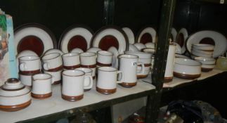 Two shelves of Denby stoneware dinner ware.