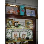 Three shelves of ceramics and two gilt framed pictures.