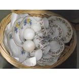 A part teaset and 3 sandwich plates with matching cups in a wicker basket