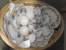A part teaset and 3 sandwich plates with matching cups in a wicker basket
