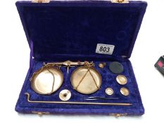 A cased set of brass postal gold weighing scales in purple velvet case