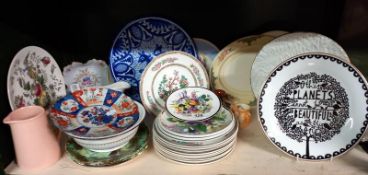 A shelf of china including other planet plate by Rob Ryan